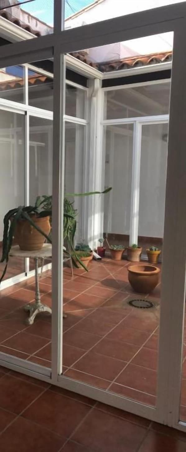 A glass door leading to a patio area with potted plants and a tiled floor.