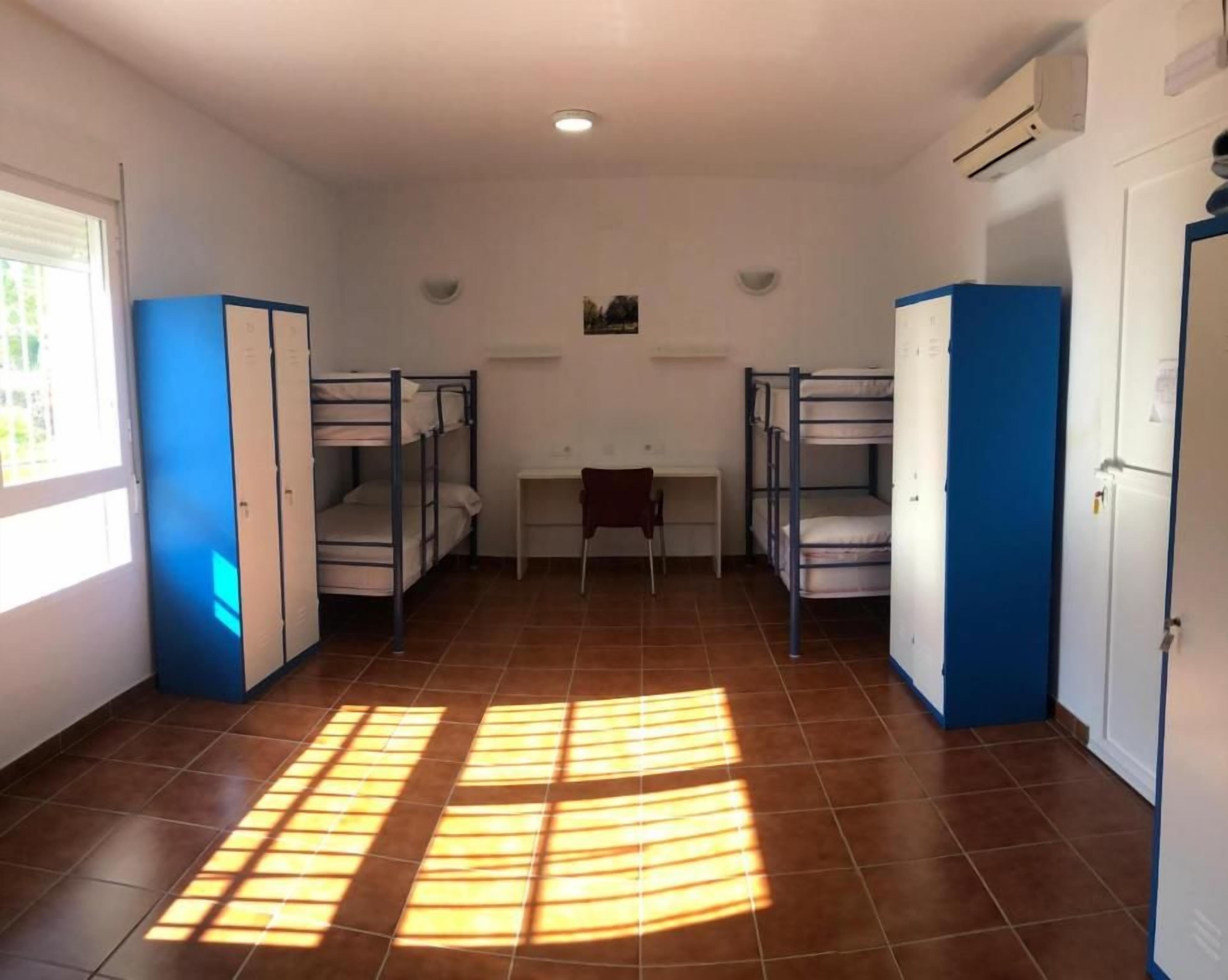 Un dormitorio con literas, un escritorio y una ventana.