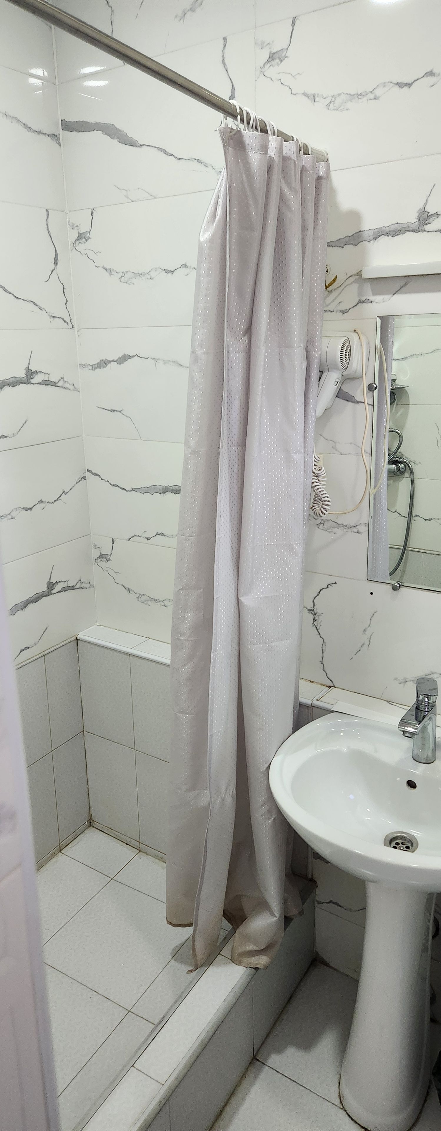 A bathroom with a shower, a sink, and a mirror.