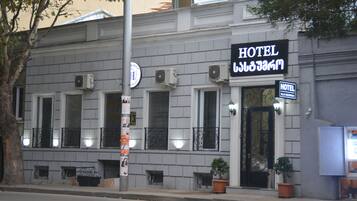 A hotel with a classic facade, multiple windows, and a prominent sign indicating its name.