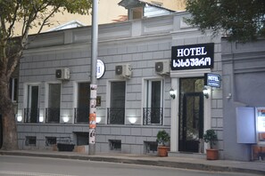 A hotel with a classic facade, multiple windows, and a prominent sign indicating its name.
