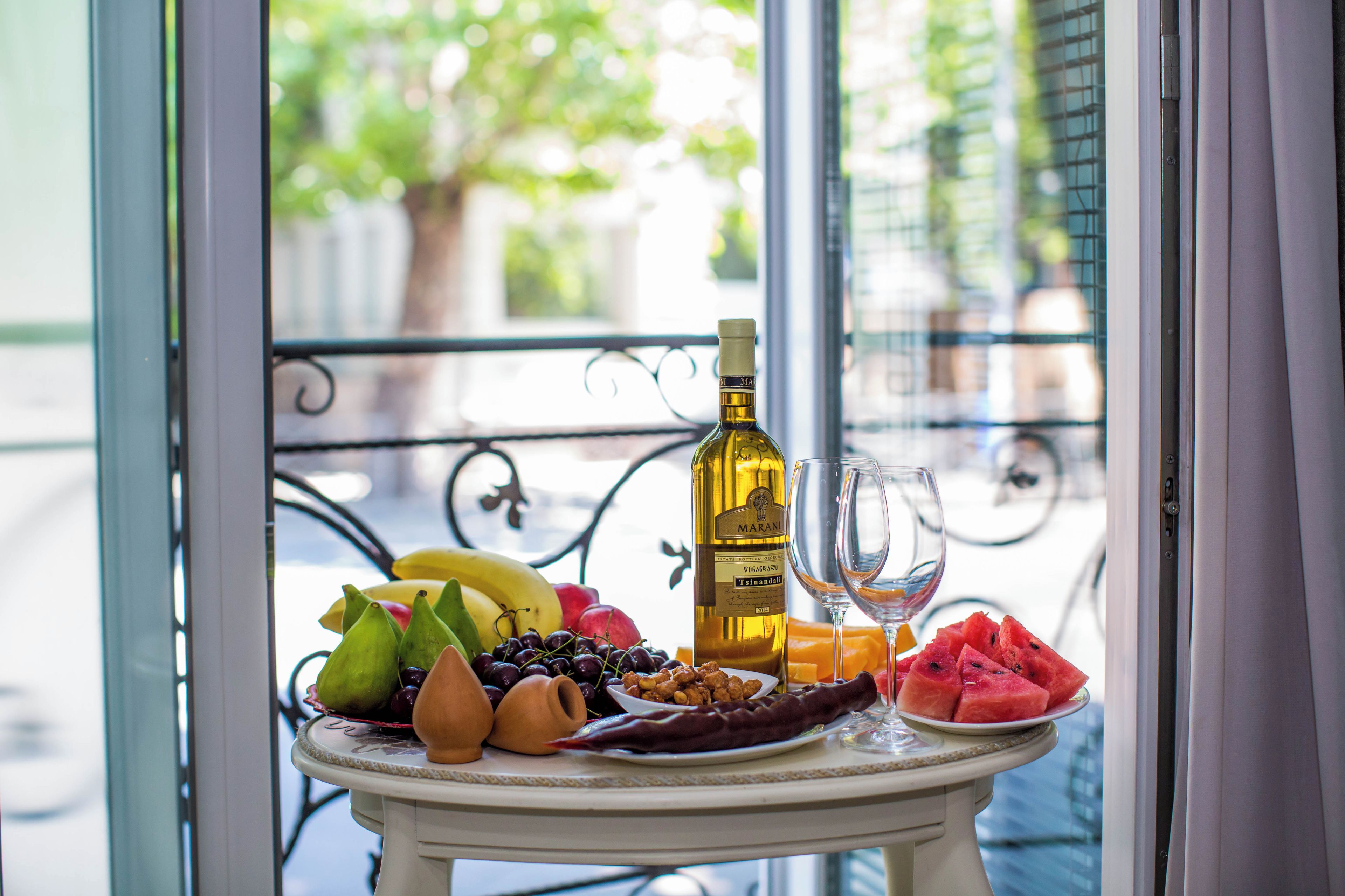 Une table avec une bouteille de vin, un verre, ainsi que divers fruits et fruits secs.