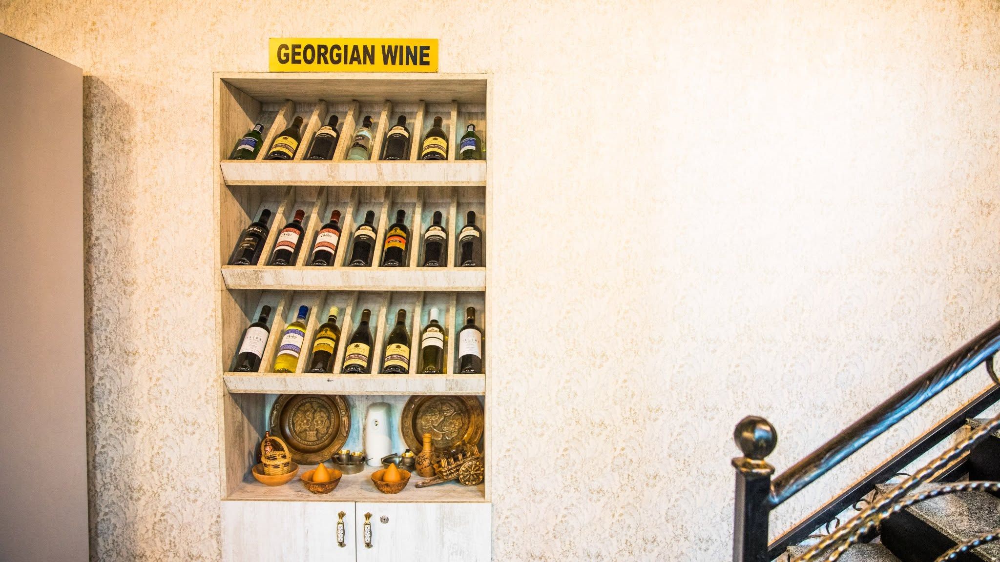 A wooden wine rack labeled 'GEORGIAN WINE' with multiple bottles.