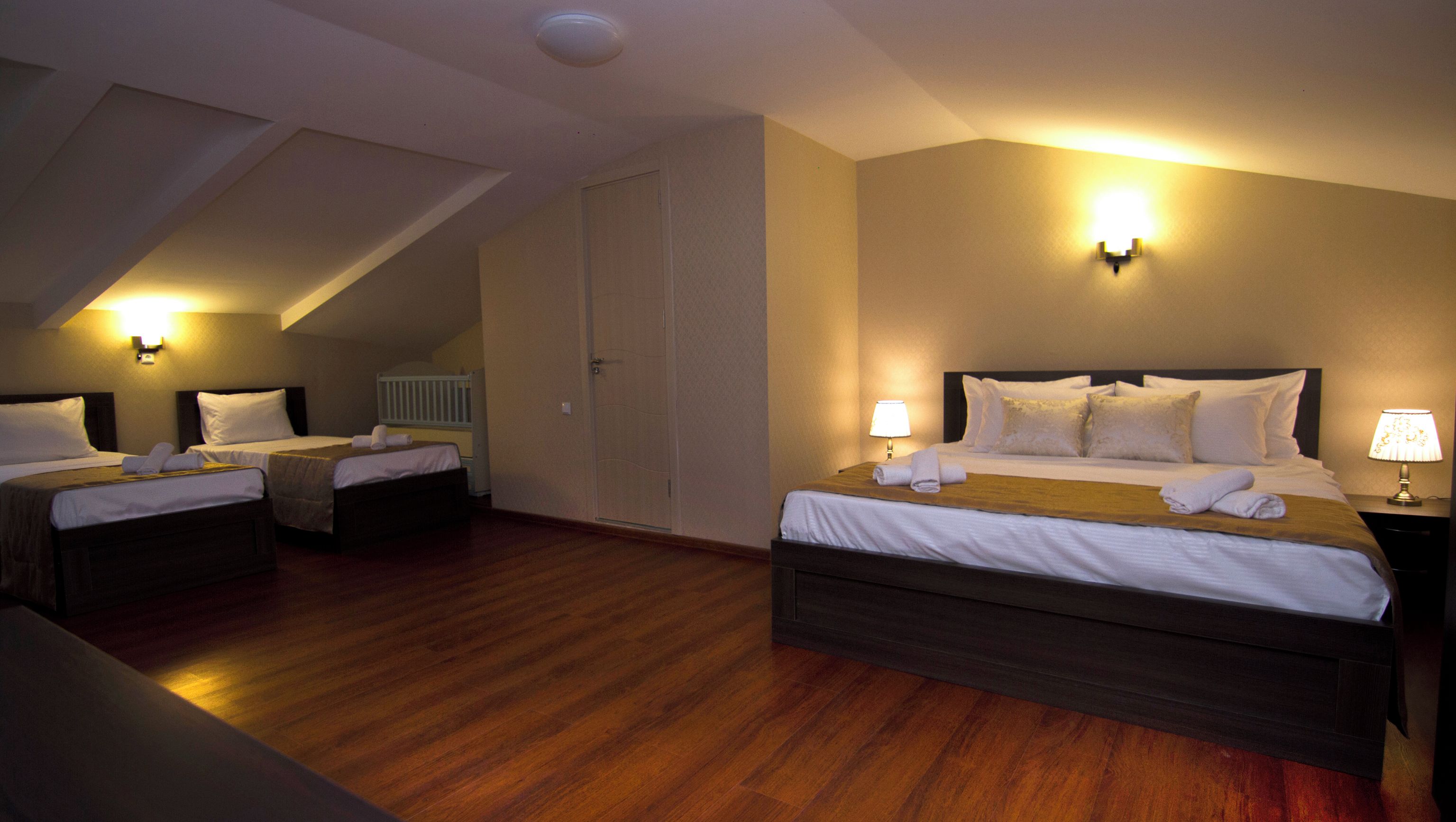 A hotel room with two beds, a wooden floor, and a sloped ceiling.