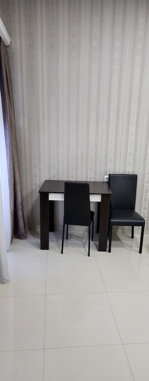 A room with a dark wooden desk, two black chairs, and a curtain with a floral pattern. - Old Georgia (Tbilisi)