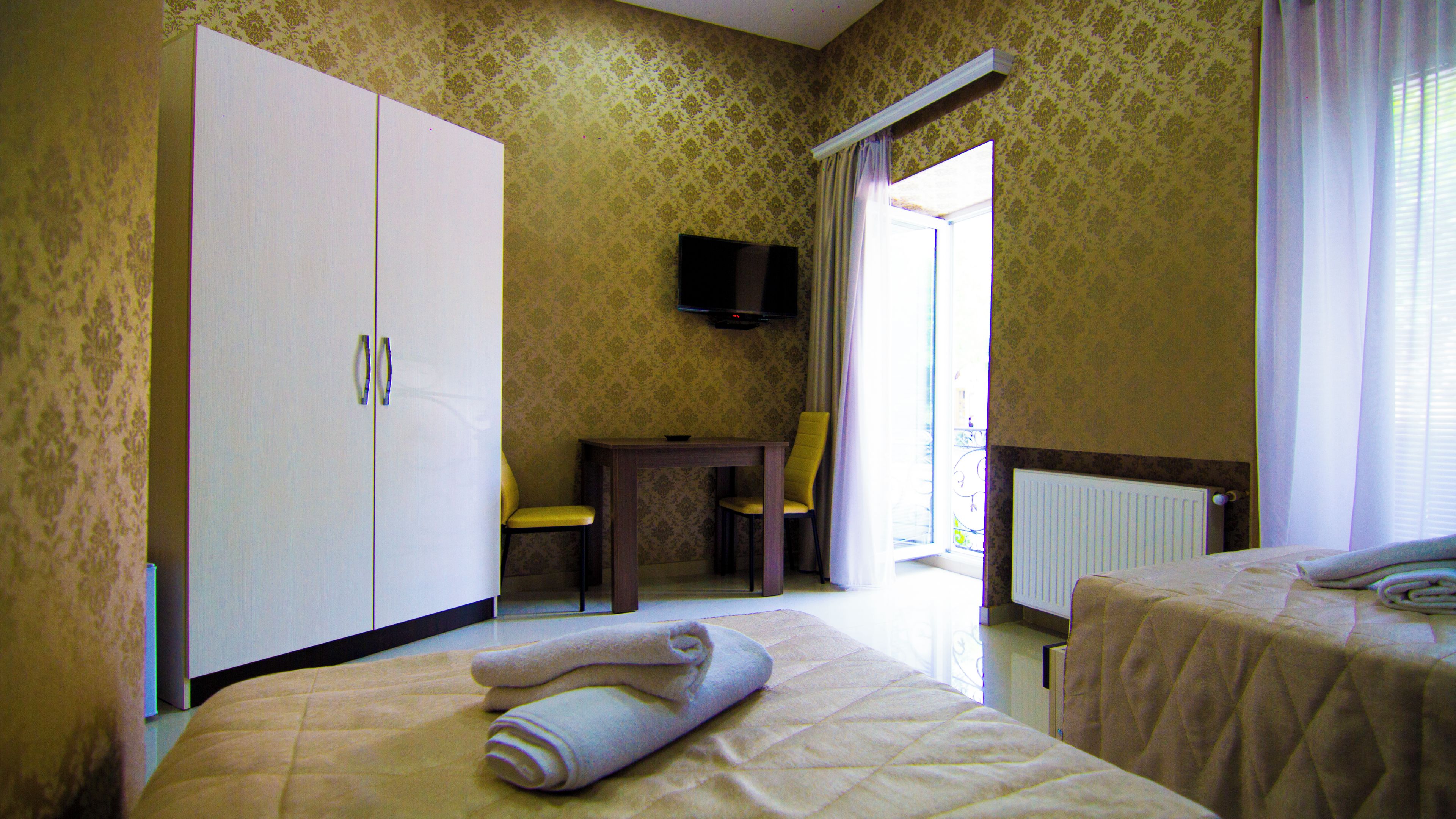A hotel room with a bed, a chair, a desk, a television, and a wardrobe.