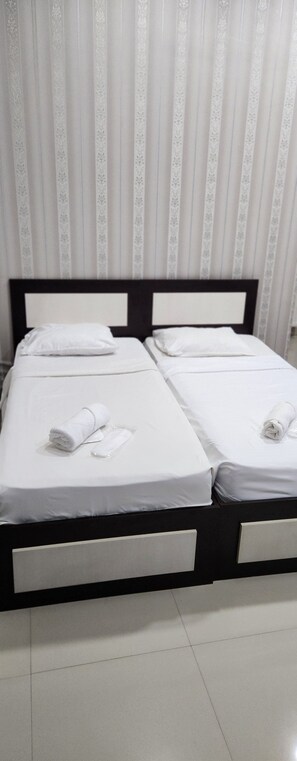 A double bed with two pillows and two rolled towels, a black headboard, and a tiled floor. - Old Georgia (Tbilisi)