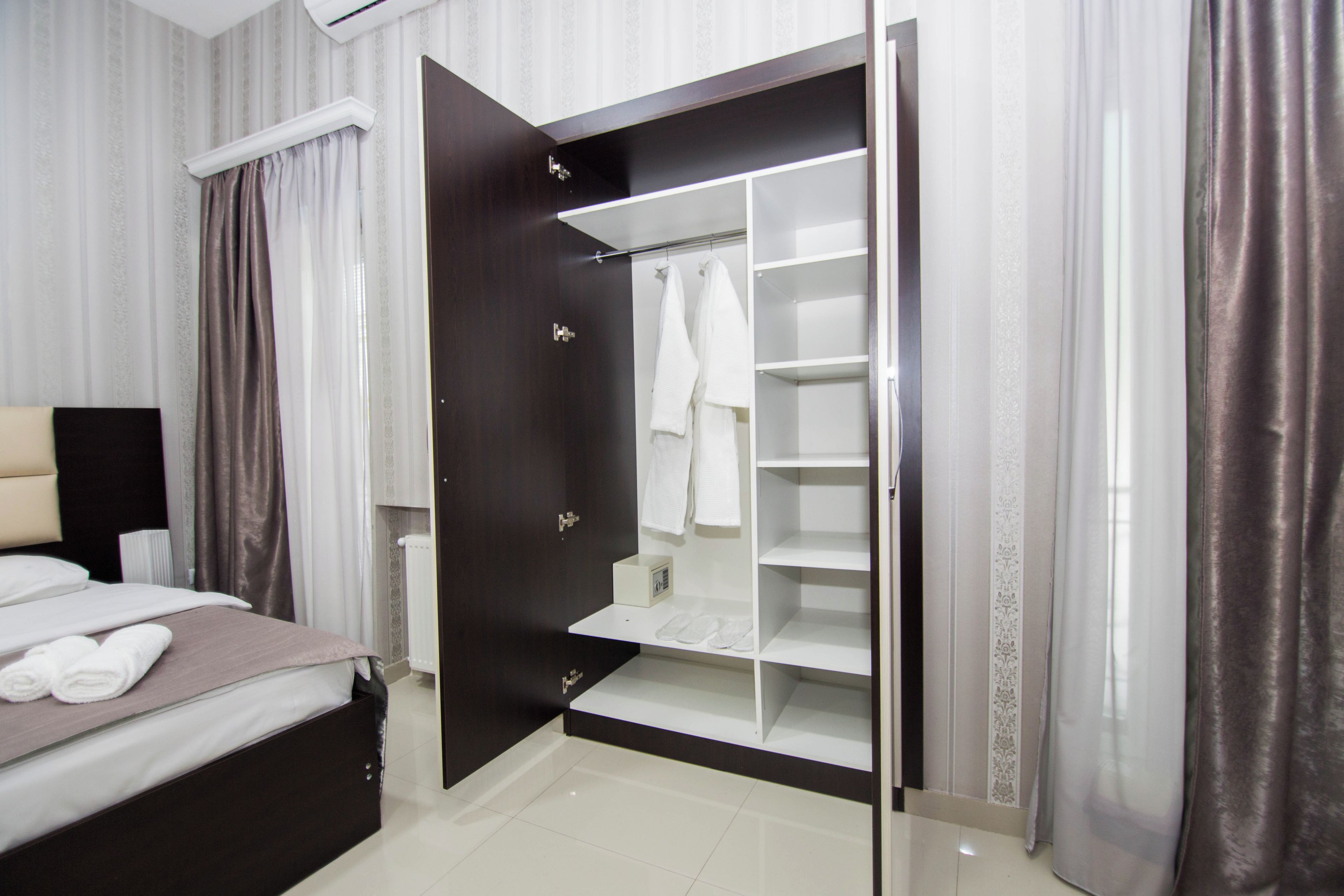 A hotel room with a bed, a wardrobe with a mirror, and a bedside table.