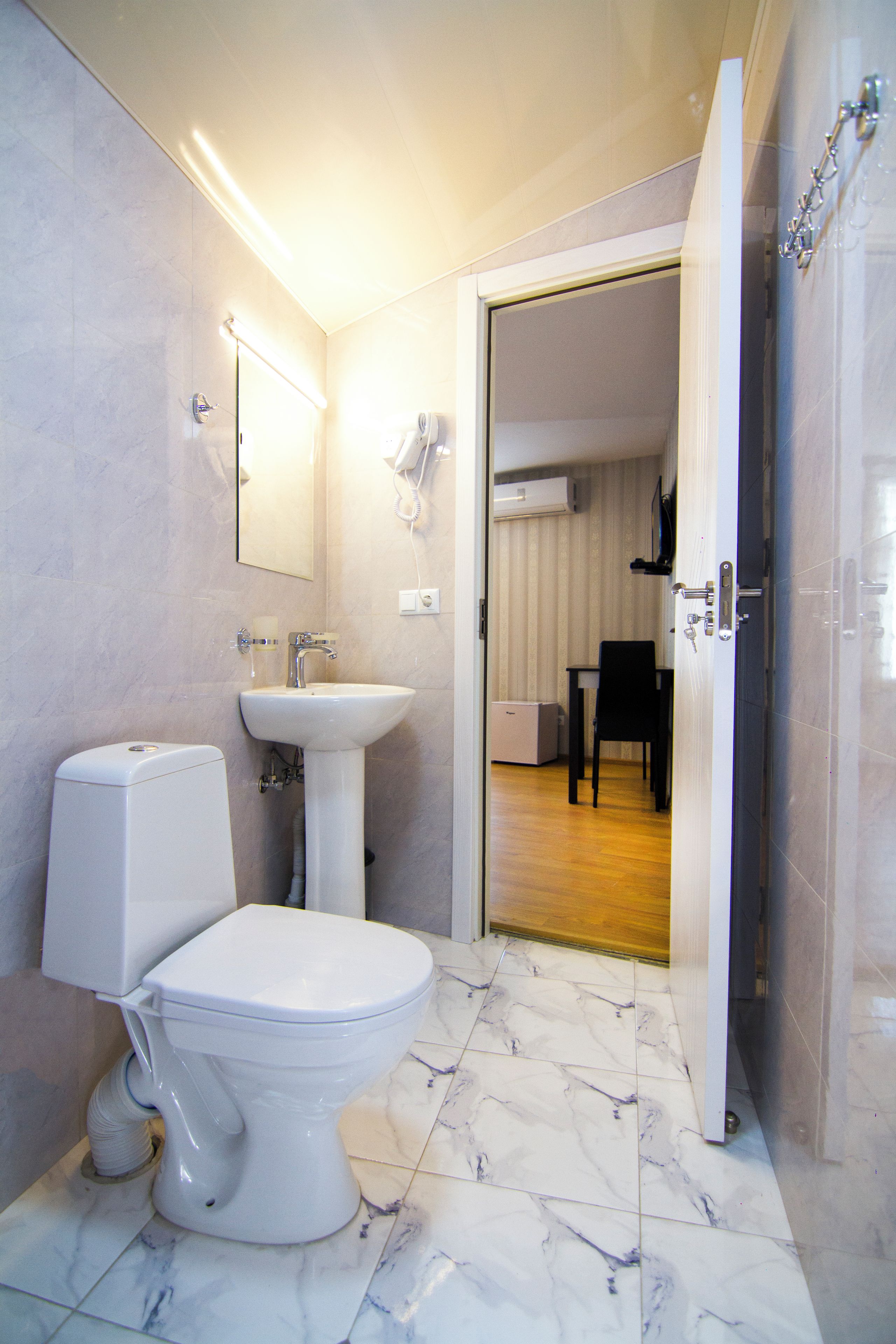 A modern bathroom with a toilet, sink, and mirror.