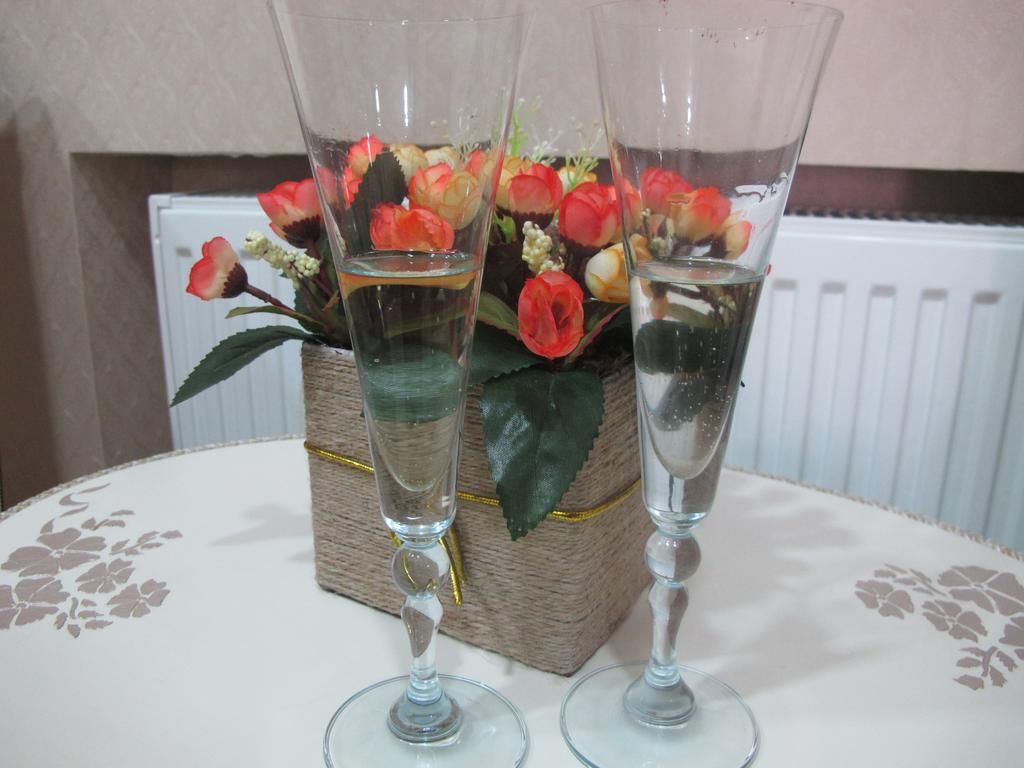 Two champagne flutes with water and artificial flowers on a table.