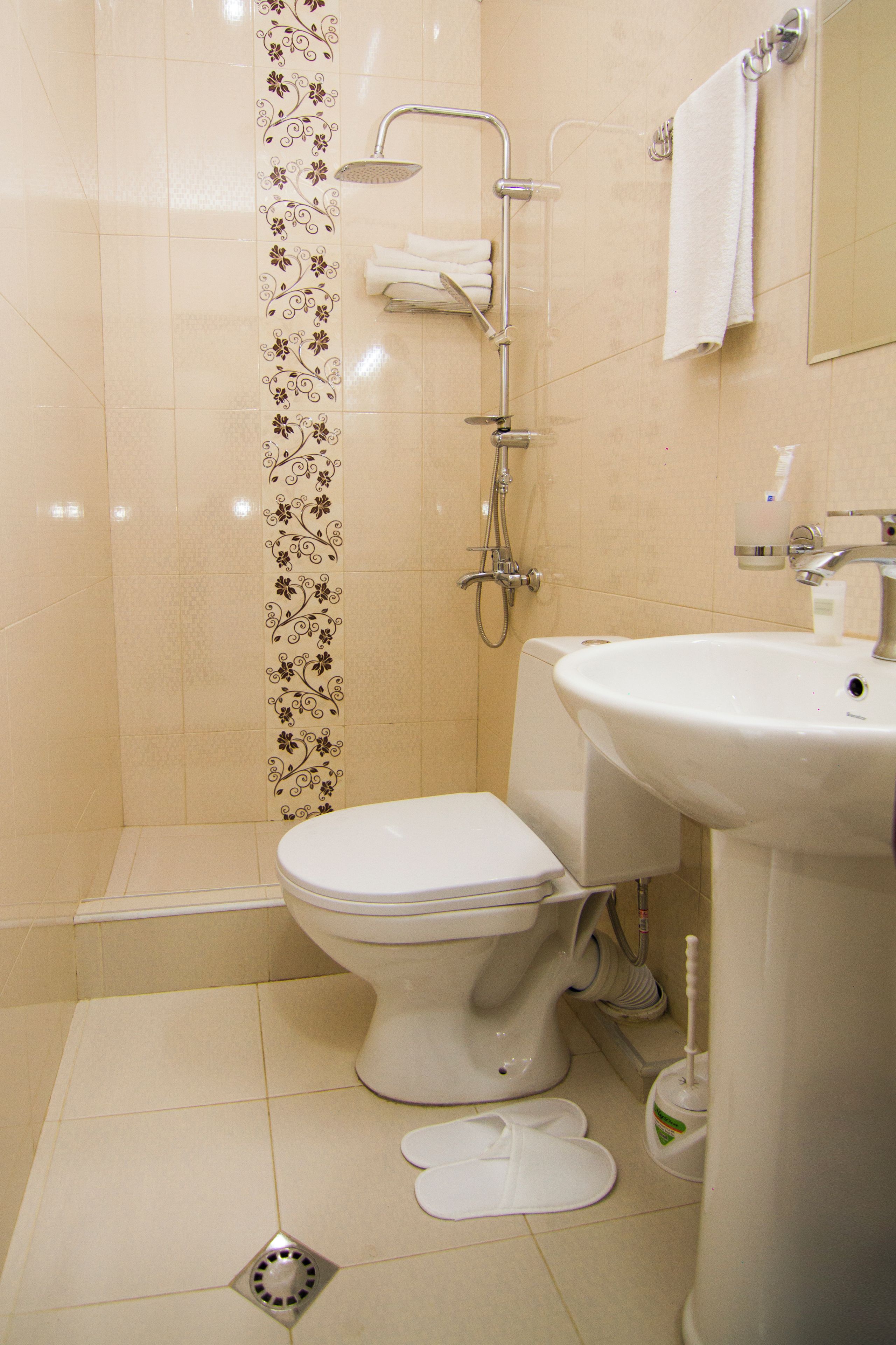 Une salle de bain comprenant des toilettes, un lavabo, une douche et un porte-serviettes.
