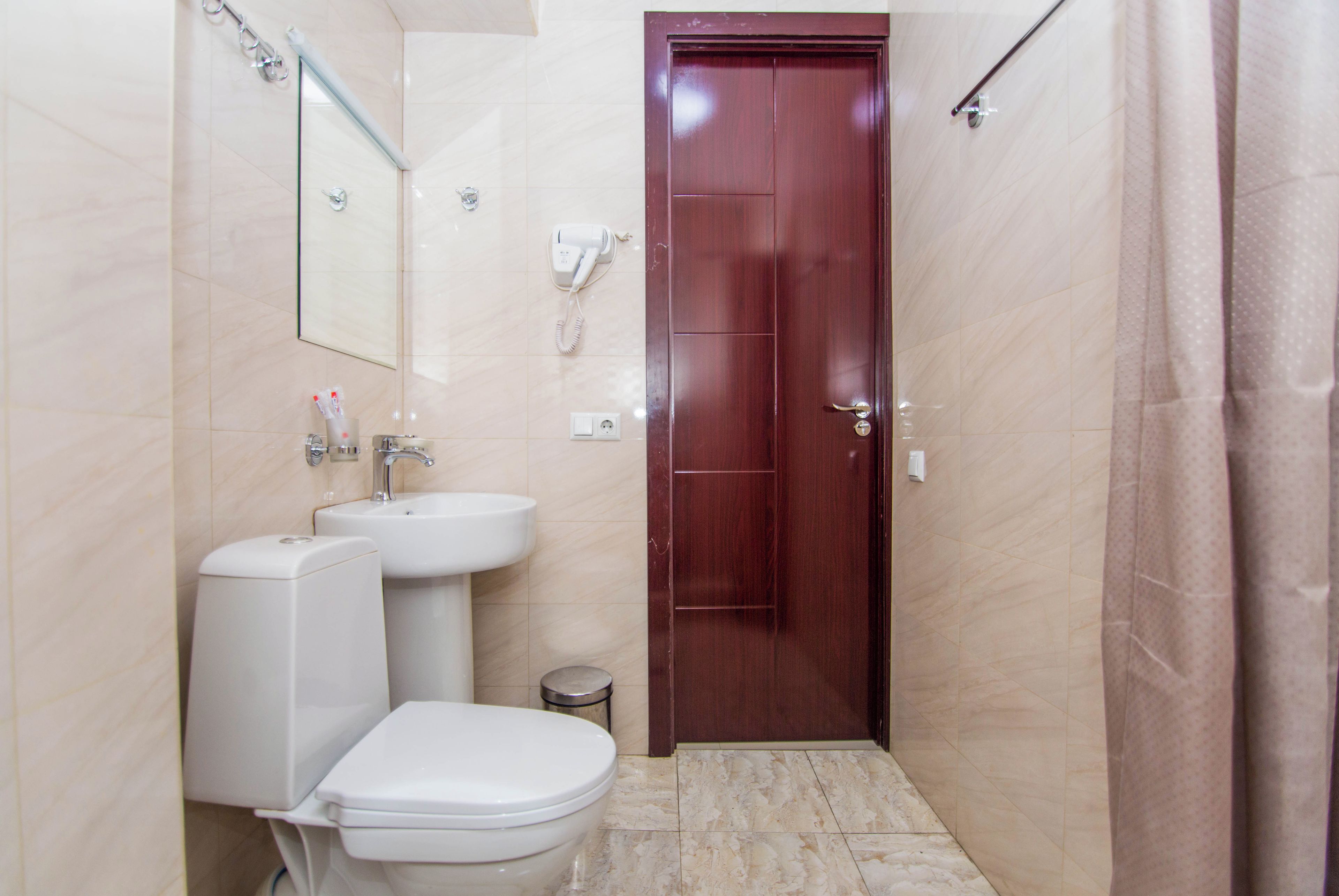 A bathroom with a toilet, sink, and a mirror.