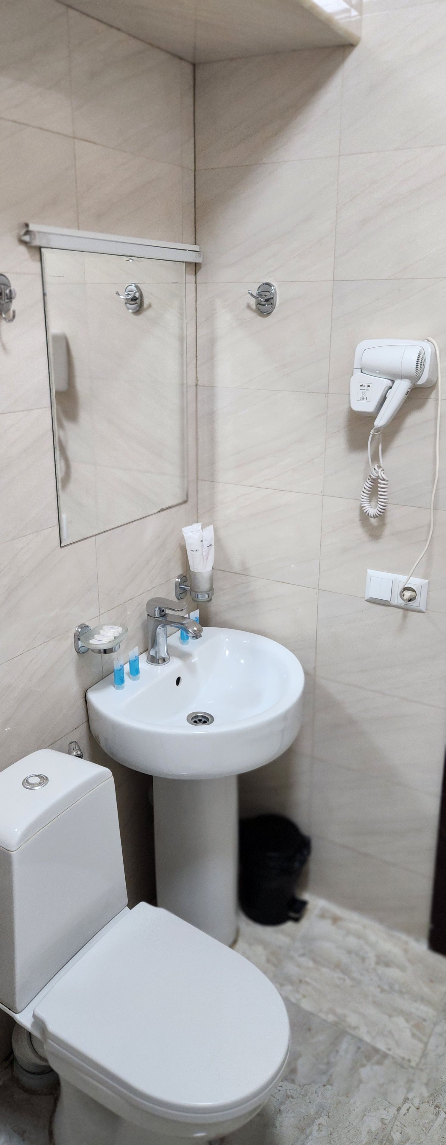 Een badkamer met toilet, wastafel en een aan de muur bevestigde haardroger.
