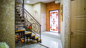 A staircase with ornate metal railings, a white door with a decorative glass panel, and a wooden door to the right.