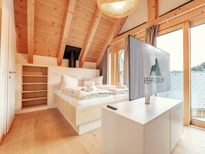 Ein Schlafzimmer mit einem Bett, einem Fernseher, einem Kleiderschrank und Blick auf ein Gewässer.