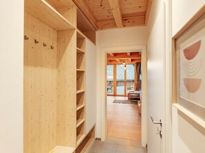 Ein Flur mit Holzbögen, einer Tür mit geometrischem Muster und Blick in einen Raum mit Bett und Balkon.