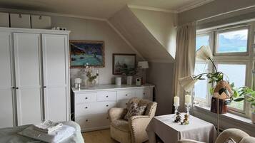 A room with a bed, a desk, a chair, a wardrobe, and a window with a view.