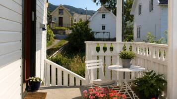 A wooden deck with a white railing, potted plants, and a table with chairs.