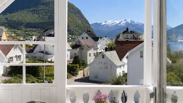 A conservatory with a table set for breakfast, overlooking a village and mountains.
