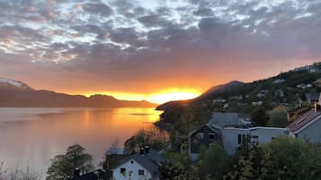 A lakeside view with houses and mountains during sunset.