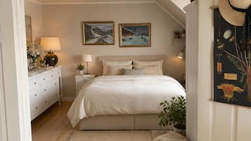 A bedroom with a bed, bedside tables, a nightstand, a lamp, a mirror, a dresser, a window, and a door.