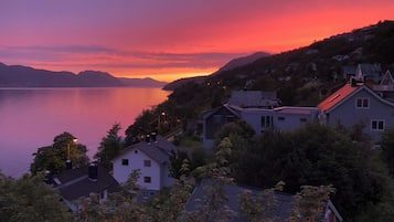 A lakeside residential area with houses, a clear sky, and a sunset.