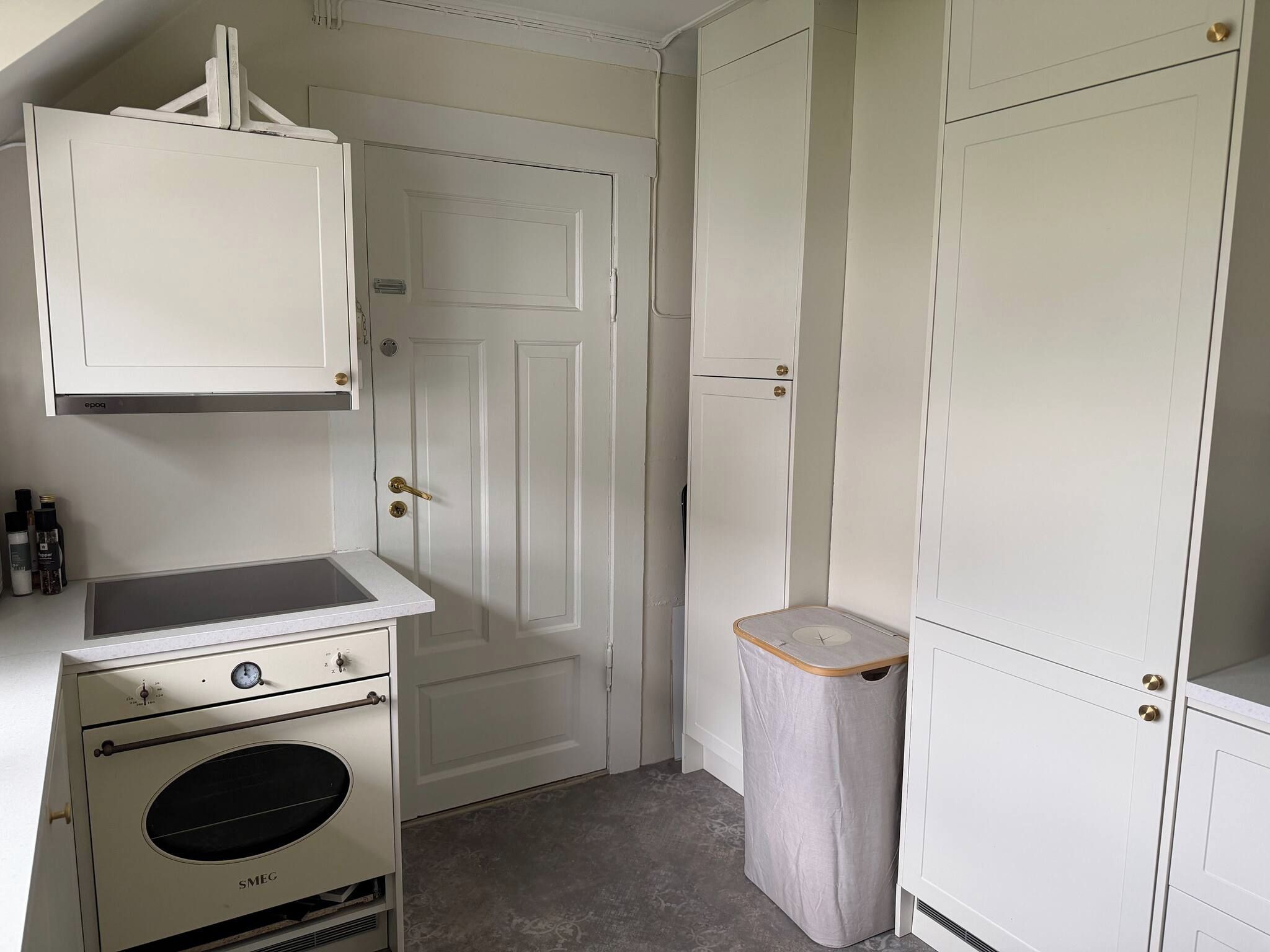 A compact kitchen with a built-in oven, a small countertop, and a trash bin.