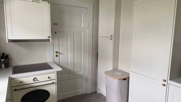 A compact kitchen with a built-in oven, a small countertop, and a trash bin.