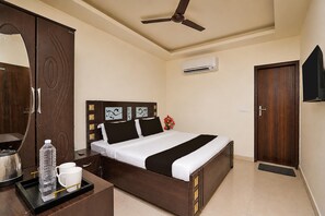 A hotel room with a bed, a wardrobe, a ceiling fan, an air conditioner, and a door. - Collection O Sector 5 Ghaziabad (Ghaziabad)