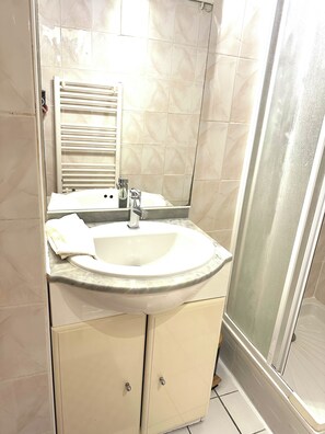 A bathroom with a sink, mirror, and shower. - Vrbo Property (Antibes)