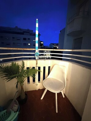 A balcony with a chair, a potted plant, and a striped railing. - Vrbo Property (Antibes)