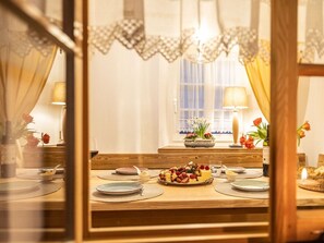A dining table set with plates, cutlery, and a centerpiece of fruit and cheese. - Holiday Home With 1 Bedroom (Grossschoenau)