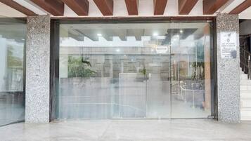 A reception area with a glass door, a reception sign, and a stone pillar with a plaque.