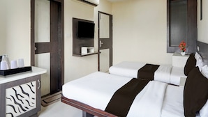 Una habitación de hotel con cama, mesita de noche, equipo de aire acondicionado y televisor.