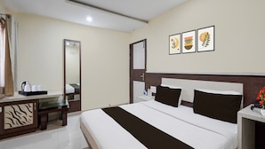 Una habitación de hotel con una cama grande, una mesita de noche, un espejo y una pared decorada con tres cuadros enmarcados.