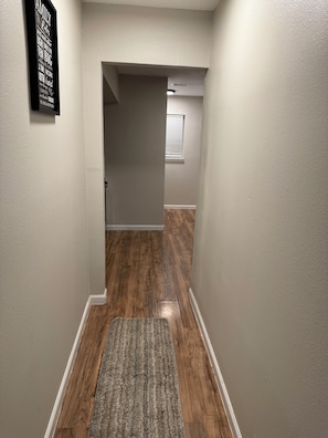 A hallway with wooden flooring, a rug, and a wall-mounted sign. - Awesome 3-bedroom house with AC in vibrant Houston (Houston)