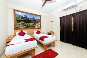 A hotel room with two beds, a large window with a view of a house and landscape, a ceiling fan, and an air conditioning unit. - Symphony Suites Grand (Bengaluru)
