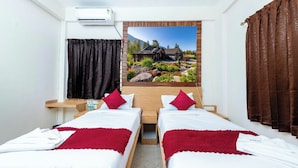 Ein Hotelzimmer mit zwei Betten, einem großen Fenster mit Blick auf ein Haus und einer Klimaanlage.