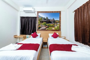 Quarto de hotel com duas camas, uma janela grande com vista para uma casa e um ar condicionado.
