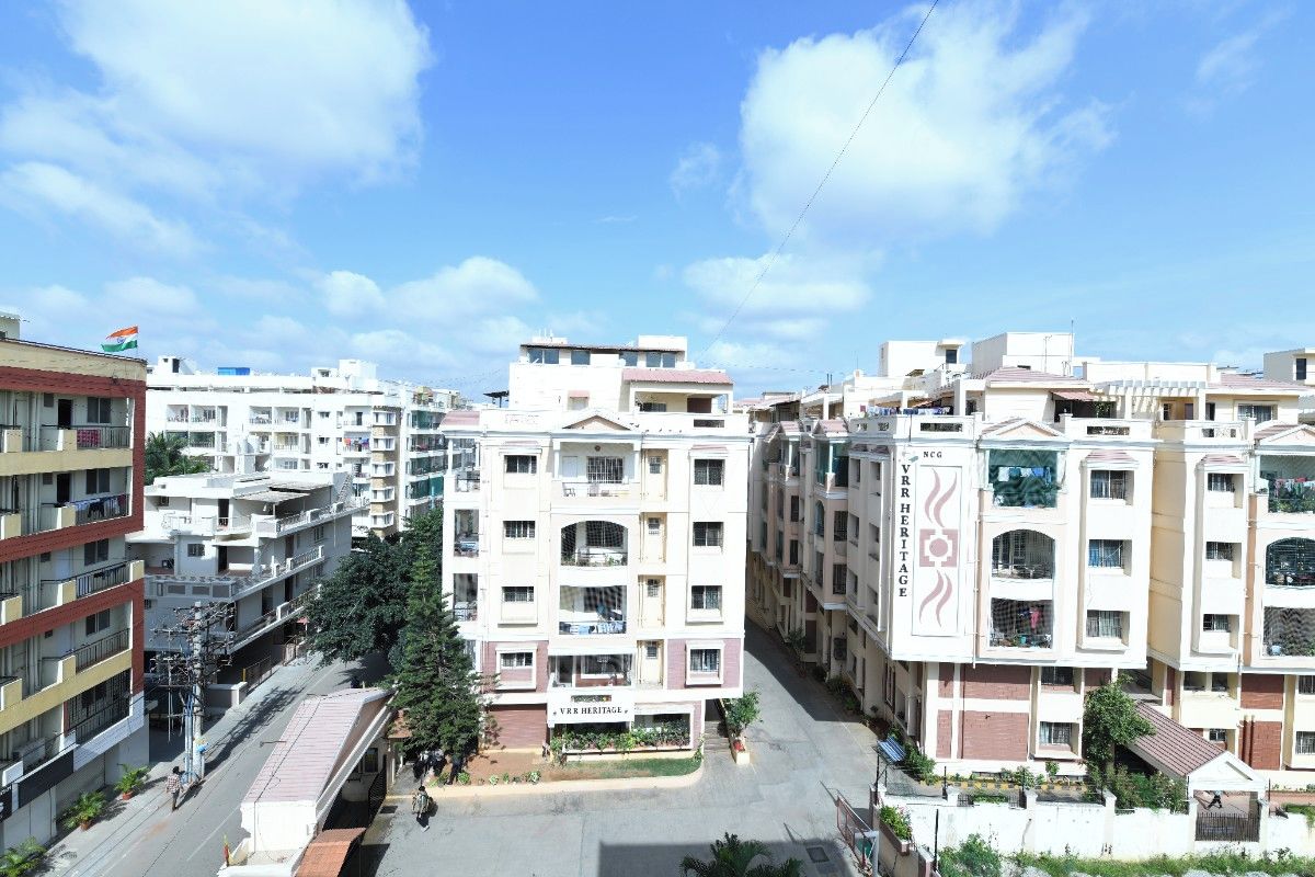 A multi-story residential building with balconies, a central courtyard, and a flag.