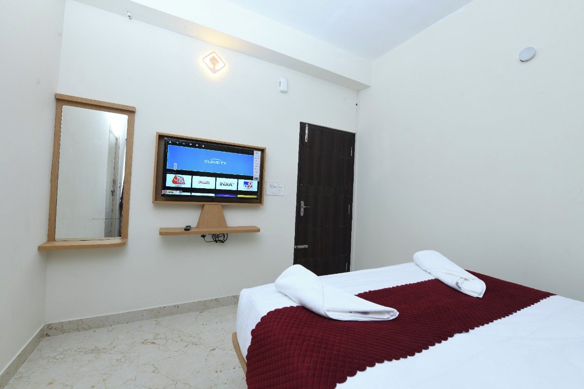 Una camera d'albergo con un letto, una televisione a parete, uno specchio e una porta.