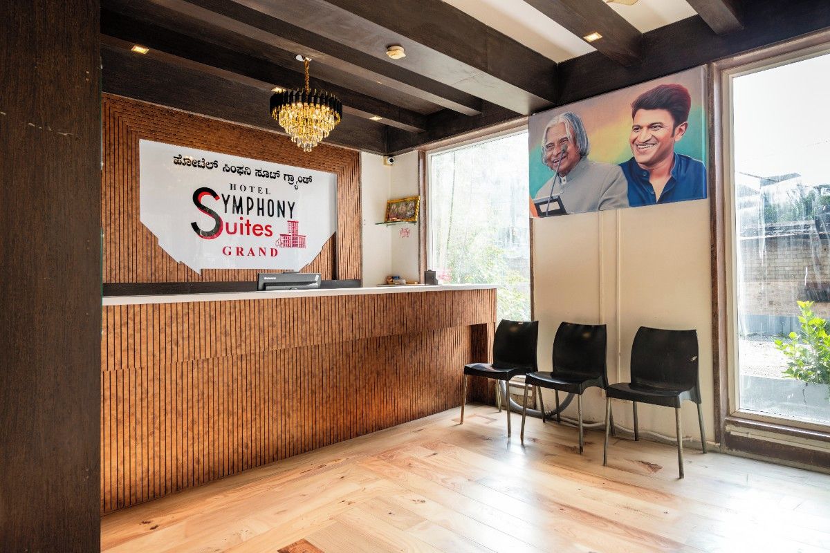 A hotel reception desk with a wooden panel design, a chandelier, and a large poster of two individuals.