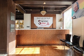 A reception desk with a sign for 'Symphony Suites Grand Hotel' and a chandelier above. - Symphony Suites Grand (Bengaluru)