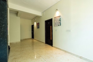 A hallway with a polished floor, a sign on the wall, and doors leading to rooms. - Symphony Suites Grand (Bengaluru)