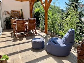 An outdoor patio with wooden furniture, a blue bean bag, and a view of a lush garden. - Vrbo Property (Wolfach)