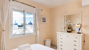 Ein Hotelzimmer mit einem Bett, einem Schminktisch, einem Spiegel und einem Fenster mit Vorhängen.