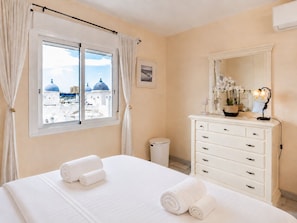 Ein Hotelzimmer mit einem Bett, einem Schminktisch, einem Spiegel und einem Fenster mit Vorhängen.