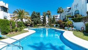 Ein Swimmingpool mit Liegestühlen und Palmen.