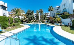 Ein Swimmingpool mit Liegestühlen und Palmen.
