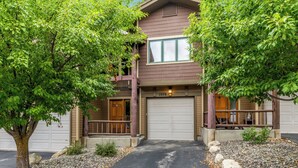 A two-story house with a garage, a porch with a railing, and a driveway leading to the entrance. - Moraine 1370 | Comfortable Mountain Townhome Near Steamboat Resort (Steamboat Springs)